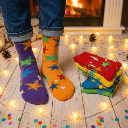 Colorful star-patterned socks on feet with a stack of similar socks on a wooden floor.