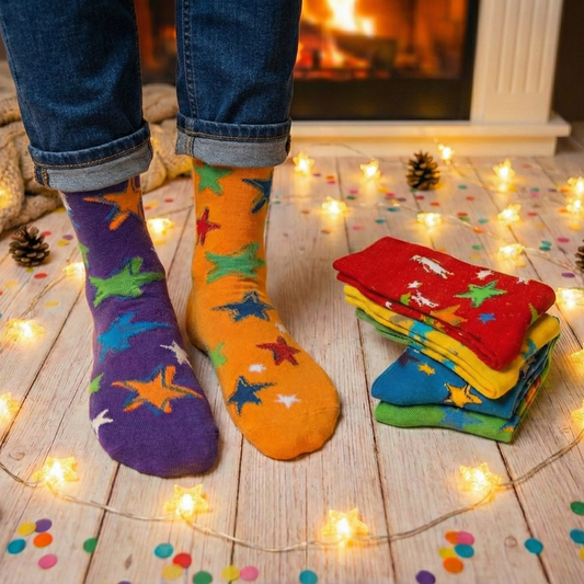 Colorful star-patterned socks on feet with a stack of similar socks on a wooden floor.